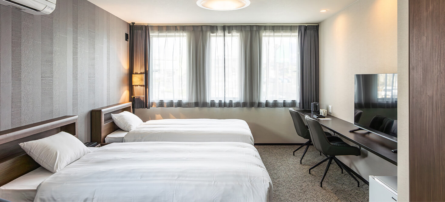 写真：2台のベッドとデスク、テレビが設置されているラージツインルーム