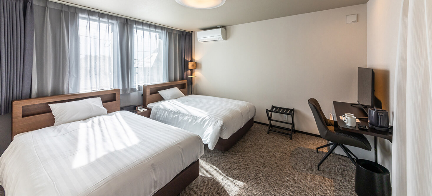 写真：2台のベッドとデスク、テレビが設置されているミドルツインルーム