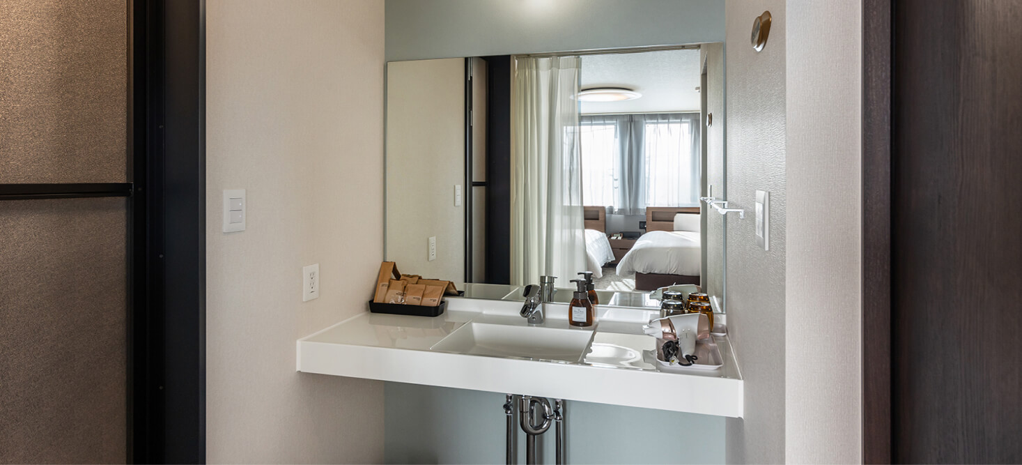 写真：ミドルツインルームのアメニティ、ドライヤーが準備されている洗面台