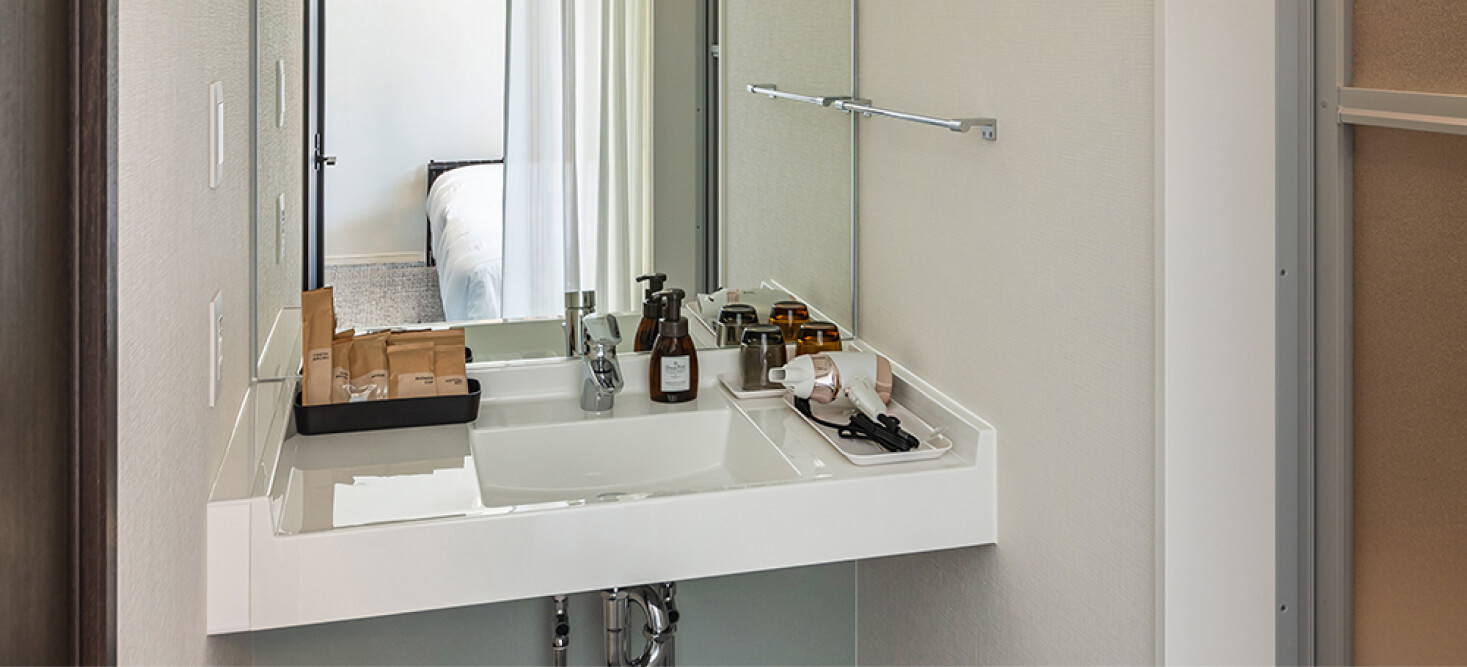 写真：スタンダードツインルームのアメニティ、ドライヤーが準備されている洗面台